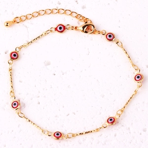 Detail of gold-plated chain bracelet featuring red enamel evil eye charms and lobster clasp