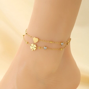 Detail of double-layer gold anklet with heart pendants and clover charm on model
