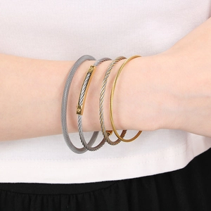 Detail showing two-tone cable twist bangles with polished metal finish and stacked style