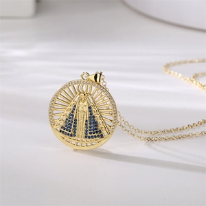 Dettaglio della collana dorata con ciondolo religioso rotondo e zircone blu incastonato