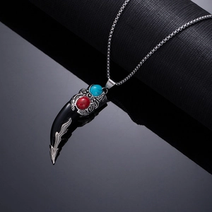 Macro view of wolf tooth pendant with silver metalwork and red turquoise stone inlay