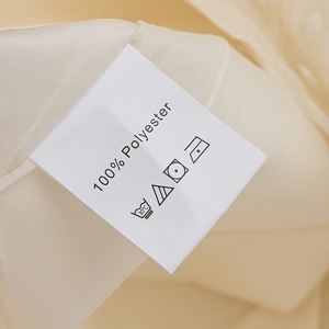 Detailed laundry care label showing 100% polyester material on beige fabric