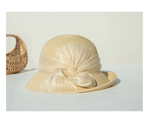 Détail d'un chapeau de paille beige avec nœud en soie et perles élégantes