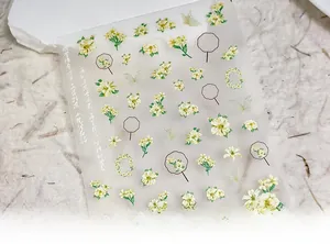 Macro shot of 5D ultra-thin nail decals featuring yellow flowers and green butterflies