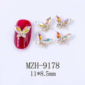 Macro detail of aurora butterfly nail charms with rhinestones on a red manicure base