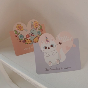 Close-up of pink and purple paper greeting cards with cute cartoon rabbit and unicorn cat