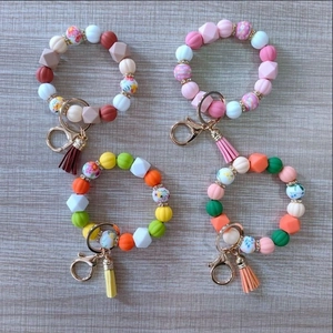 Detail of beaded keychains with silicone pumpkin beads and leather tassels on wood