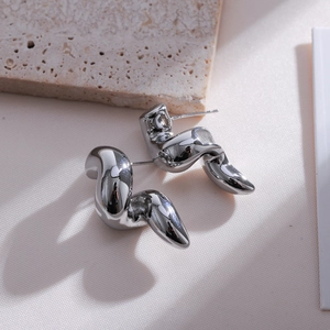 Macro shot of silver irregular double-layer water drop earrings on stone and fabric