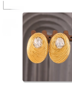Detailed view of vintage gold plated oval earrings with bird nest texture and crystal stone
