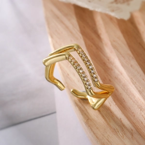 Detailed shot of gold-plated double-layer ring with sparkling zircon inlays on wooden stand