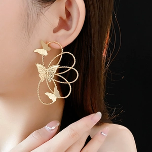 Detailed model shot of gold hollow flower earrings with butterfly motifs and metal wires