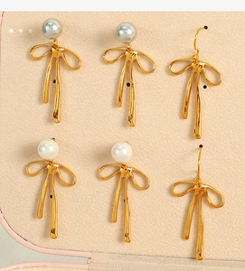 Detailed view of golden bow earrings with white and grey pearls in a jewelry box