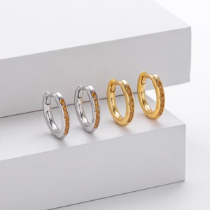 Macro detail of S925 silver gold and silver hoop earrings with yellow cubic zirconia