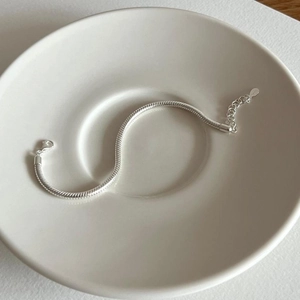 Close-up of S925 sterling silver snake bone chain bracelet on a ceramic plate