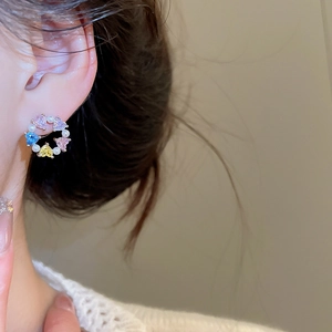 Close-up of model wearing heart-shaped colorful zircon and pearl wreath earrings