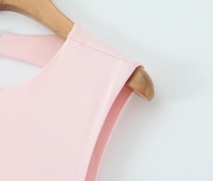 Détail de la couture d'épaule et texture du tissu de la robe rose sur un cintre