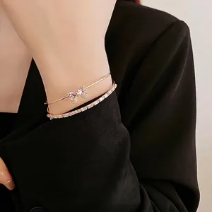 Pink zircon bow open bangle featuring a gold double-layer stacked design on wrist