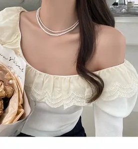 Gros plan d'un collier de perles double épaisseur porté avec un haut en maille