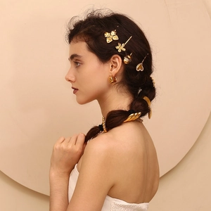 Detail of 18K gold plated heart and floral hair clips styled on braided hair