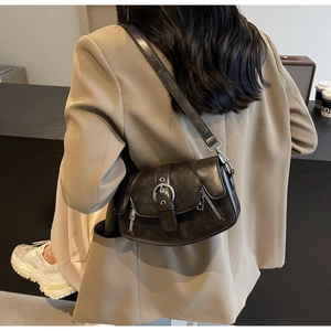 Detailed back view of a vintage black leather saddle bag with metal buckle on a model