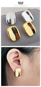 Polished geometric brass earrings in gold and silver finish shown on ear
