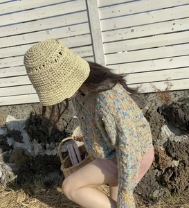 Detail of hand-crocheted beige straw bucket hat with textured knit summer pattern