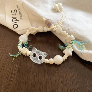 Close-up of ceramic cat bead bracelet with heart and star charms on woven rope
