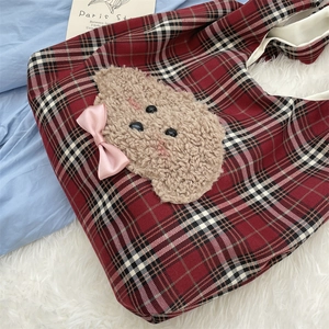 Detail of red checkered tote bag featuring a 3D plush puppy patch and pink satin bow