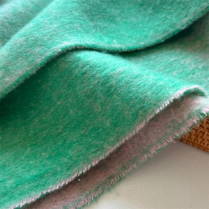 Macro view of thick green cashmere-like scarf fabric with sawtooth edges and soft texture