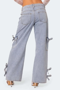 Detail view of denim cargo pants featuring stylish bow tie straps on side pockets