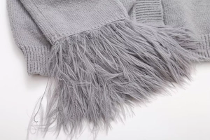 Gros plan sur la maille grise avec franges en fausse fourrure sur ce cardigan