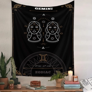 Detail of a black Gemini zodiac tapestry with gold symbols in a cozy room setting