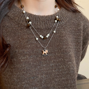Détail des perles d'oeil de tigre et pendentif cheval en bois sur collier de perles