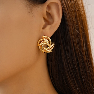 Close-up of golden spiral twist geometric earring worn by a model in soft lighting