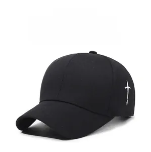 Detail of white cross embroidery on the side of a black cotton baseball cap