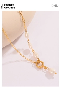Close-up of gold paperclip chain necklace with baroque pearls and circular clasp