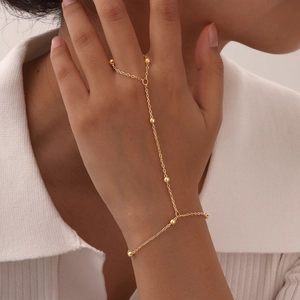 Detailed view of 18K gold plated hand harness with minimalist bead chain on female model