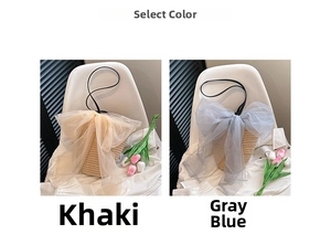 Detail of woven straw bucket bag featuring a large organza bow and slim shoulder strap
