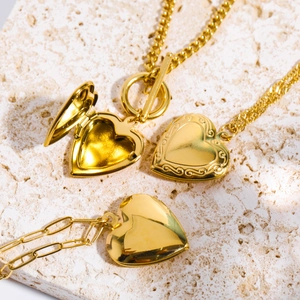 Golden heart locket necklaces in polished and embossed styles on stone background