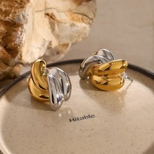 Macro shot of two-tone twisted knot earrings on a ceramic dish with mineral stone
