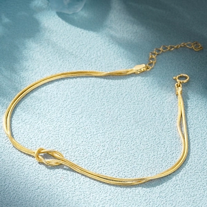 Close-up of golden double-layered snake chain bracelet with a central knot design