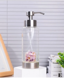 Detail of glass lotion dispenser with stainless steel pump and purple crystal stones