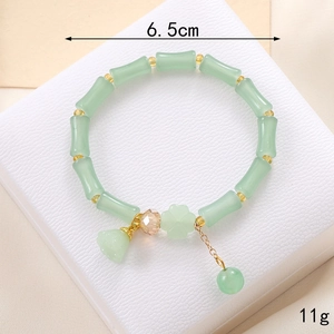 Détail d'un bracelet en cristal vert en forme de bambou avec breloque fleur de muguet