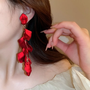 Detail of elegant red petal tassel earrings worn by a model in a luxury style