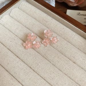 Gros plan de boucles d'oreilles fleurs en résine rose dans un écrin en velours beige