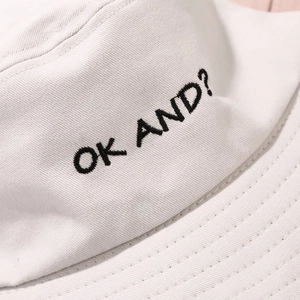 Detail of OK AND embroidery and textured twill cotton fabric on beige bucket hat