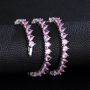 Macro shot of silver tennis chain featuring pink heart gemstones on black leather roll