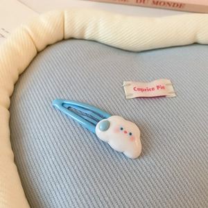 Détail d'une pince à cheveux nuage bleu avec un charmant motif en résine 3D souriant