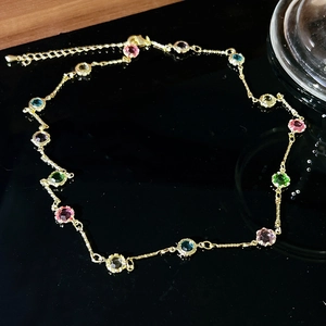 Detailed view of gold chain with multi-colored round zircon stones and adjustable clasp