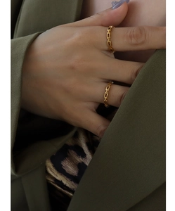 Detail shot of stacked 18k gold chain link rings on model with olive suit